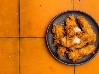 Chicken tenders, deep fried strips from breast fillet. orange background. top view.