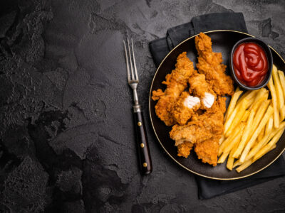 Deep fried chicken strips, sticks with french fry and sauce. black background. top view.